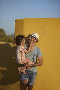 父亲抱女儿靠墙站立爱高清图片素材