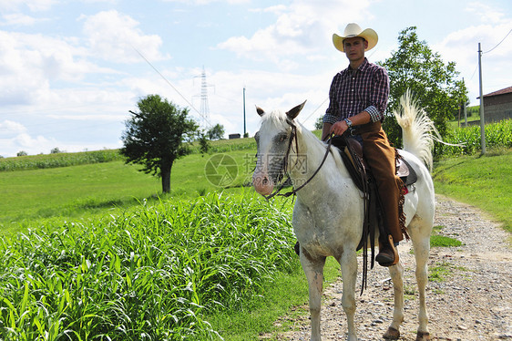在农村路上骑马的牛仔图片