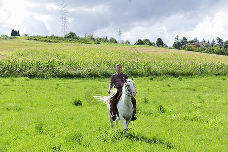 年轻男子骑着马在野外奔跑图片