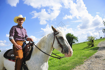 在农村路上骑马的牛仔装男子图片