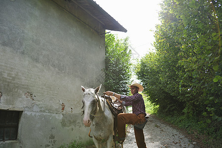 年轻人在谷仓外骑马图片