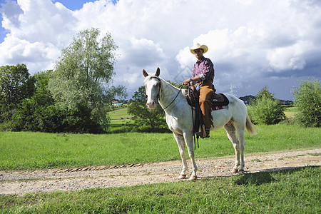 年轻男子骑着马在土路上图片