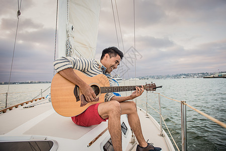 乘帆船上弹吉他的年轻人图片