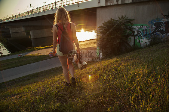 在桥和河边行走的年轻妇女图片