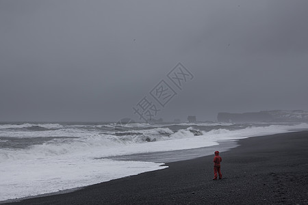 穿红衣服的人站在沙滩上面对大海图片