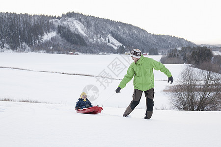 父亲和儿子在雪中玩耍图片