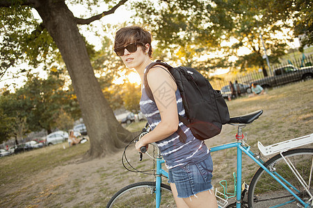女性推着自行车路过公园图片