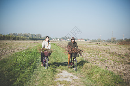 在农村道路骑自行车的年轻夫妇图片
