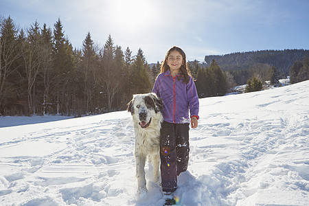 享受在雪中玩耍的儿童和狗狗图片