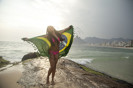 海滩上持有巴西国旗的年轻女性图片