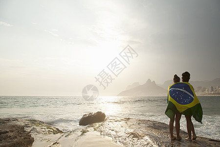在海滩包裹着巴西国旗的额两名年轻女性图片