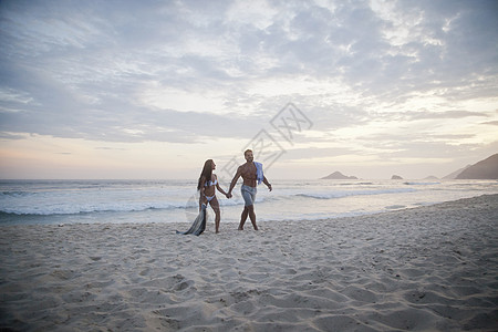 站在海边沙滩散步的情侣图片