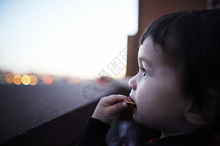 男孩靠在窗边吃饼干图片