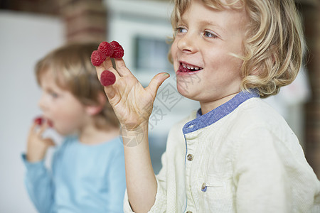 两个男孩在吃指尖上的树莓图片