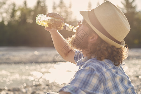 穿着帽子喝啤酒瓶的中年男子侧边景图片