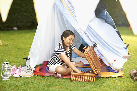 女孩在花园自制帐篷前准备野餐篮子图片