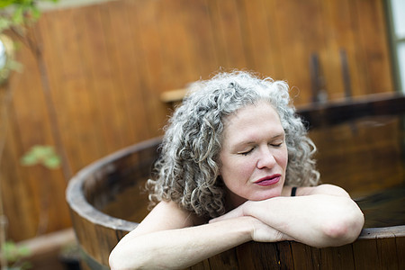 成熟的女子在生态休养时躺在热浴缸里着图片