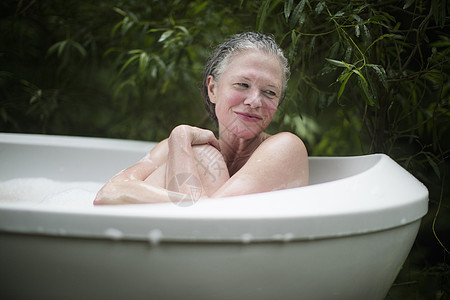 成熟的女人拥抱膝盖在花园泡浴图片