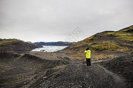 在冰岛Solheimajajokol拍摄冰川照片的男游客图片