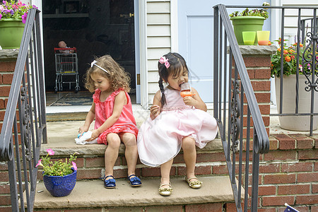两个女孩坐在台阶上吃冰棒背景图片