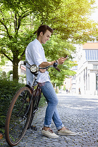 年轻人的侧面观仰视自行车智能手机微笑背景图片
