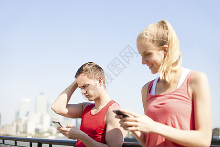 在桥上使用智能手机的运动者图片