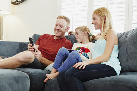 在客厅沙发上聊天看手机的一家人图片