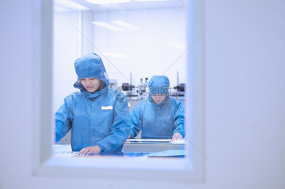 女工在灵活电子设备工厂清洁室检查弹电路图片