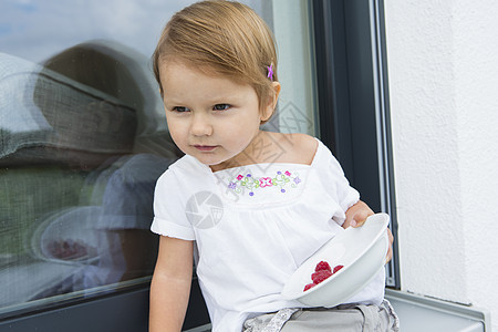 坐在院子里吃草莓的雌幼女肖像图片