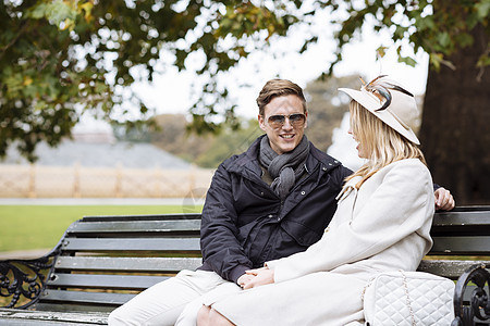 坐在公园长椅上的时尚年轻夫妇图片