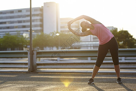 年轻女跑者在路边做伸展运动图片