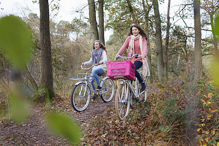 女孩们骑自行车其中一个有粉红色箱背景图片