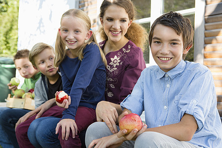 坐在吃苹果的院子里青少年和儿童图片