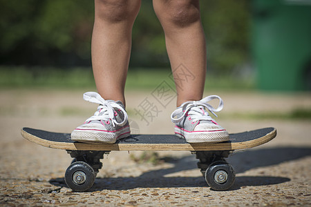 身着帆布鞋的女孩腿站在滑板上背景图片