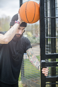 成人男子站在栅栏上用篮球挡着栅栏图片