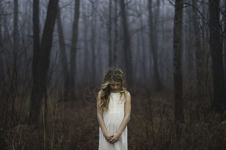 在迷雾的森林中低头的女孩图片