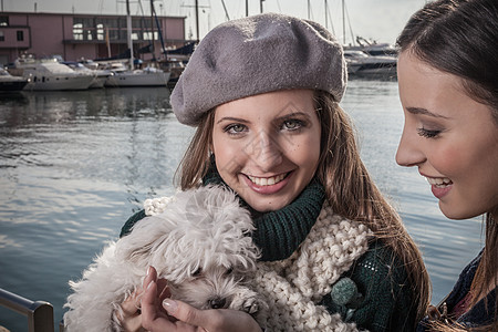 在船坞戴着贝雷帽的年轻女子抱着狗看镜头微笑图片