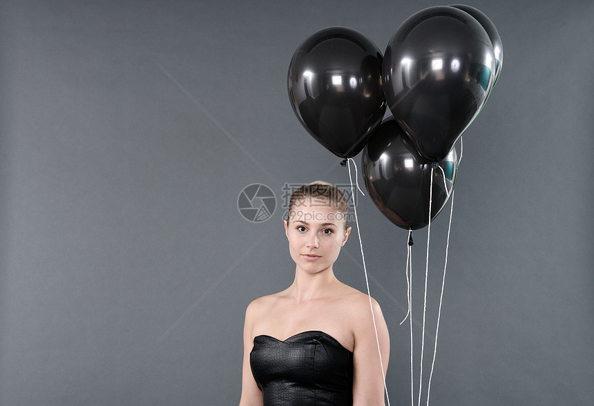 有黑色气球灰背景的年轻女子图片