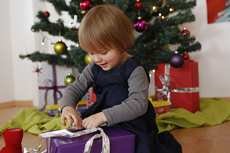 女孩在圣诞树下开礼物盒子图片