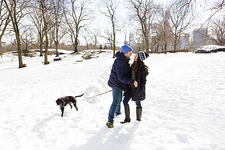 美国纽约中央公园站在雪地上遛狗的情侣图片