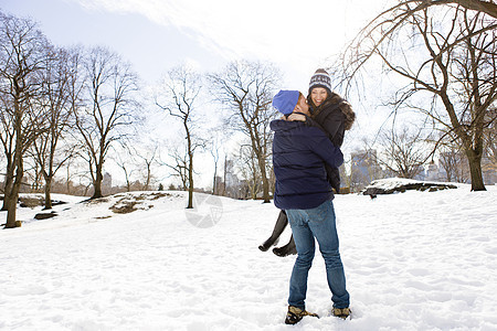 美国纽约中央公园站在雪地上丈夫抱起妻子牛仔裤高清图片素材