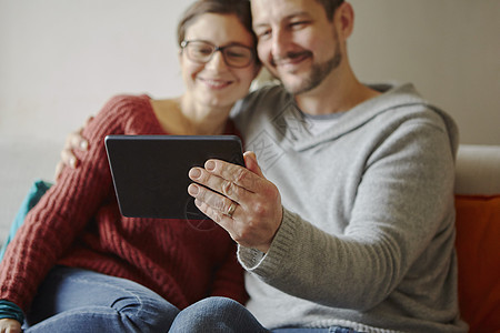 坐在沙发上用数字平板电脑自拍的成人中年夫妇图片