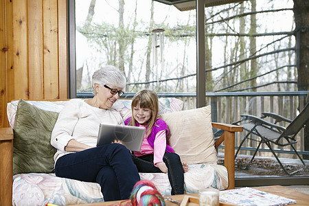 祖母和孙女在客厅沙发上看平板电脑图片