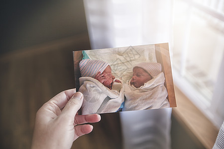 手持双胞胎婴儿照片的母亲图片