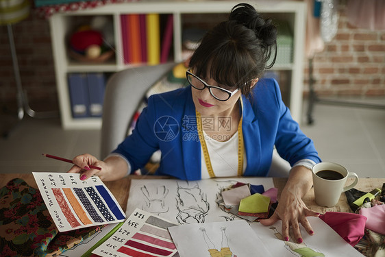 在设计室工作的妇女坐在办公桌旁看样布图片