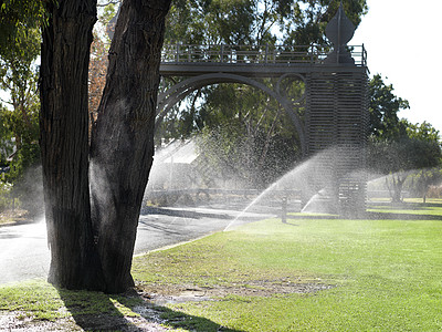在公园草坪上浇水的喷洒器图片