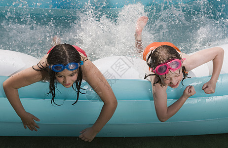两个女孩趴在划水池边用脚扑腾水图片