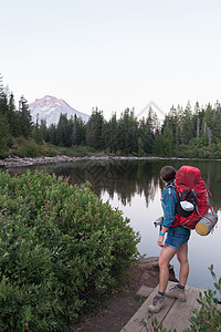 美国俄勒冈州胡德山森林年轻的女徒步旅行者眺望湖面图片