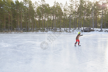 男孩在冰冻湖上滑行图片