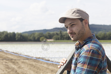 农民在田里肩扛着水管图片